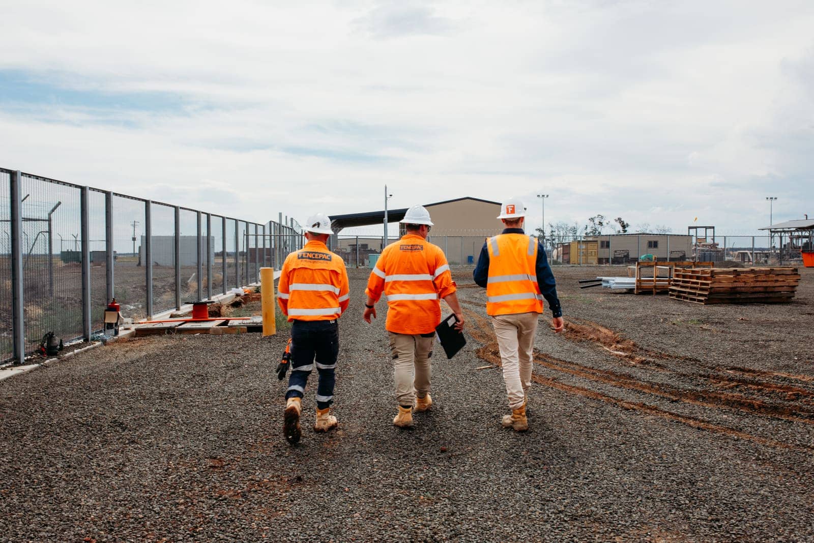 Three Fencepac staff walking along a new security fence line at a gas facility
