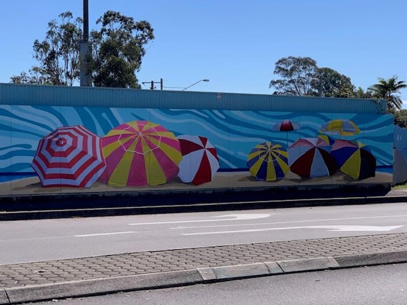 Construction hoarding with beach umbrella mural
