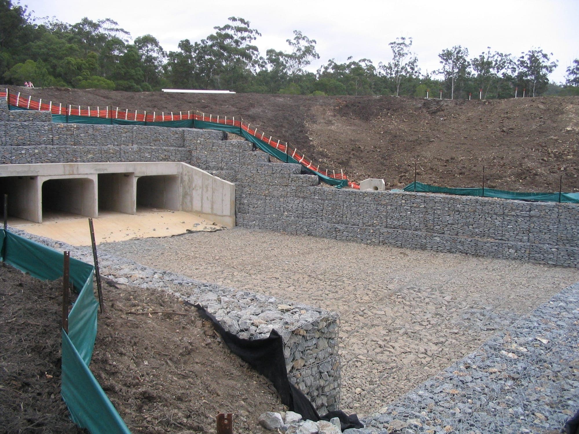 Massive gabion retaining wall aerial view with red earth and bushland