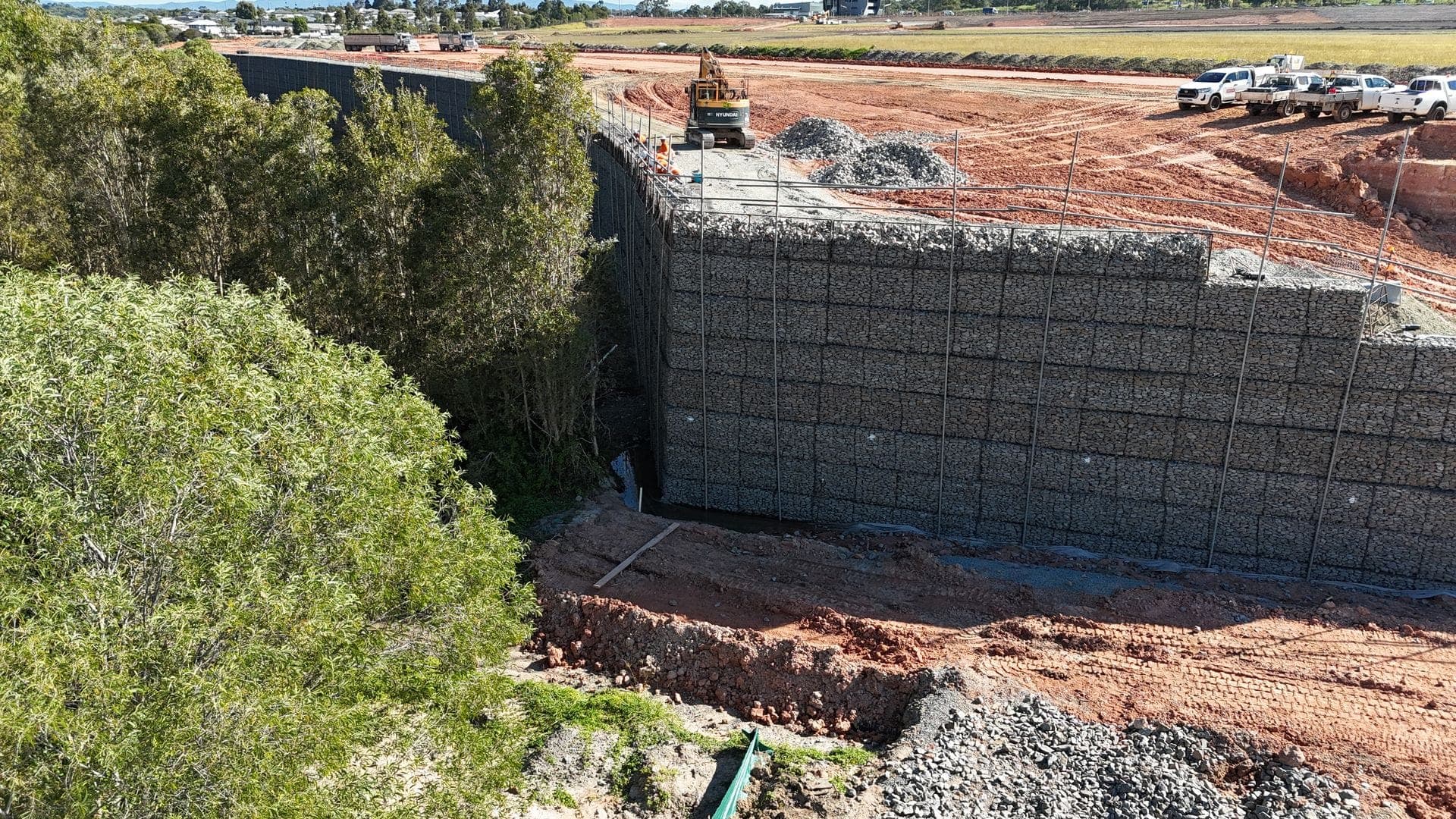 Massive gabion retaining wall aerial view with red earth and bushland