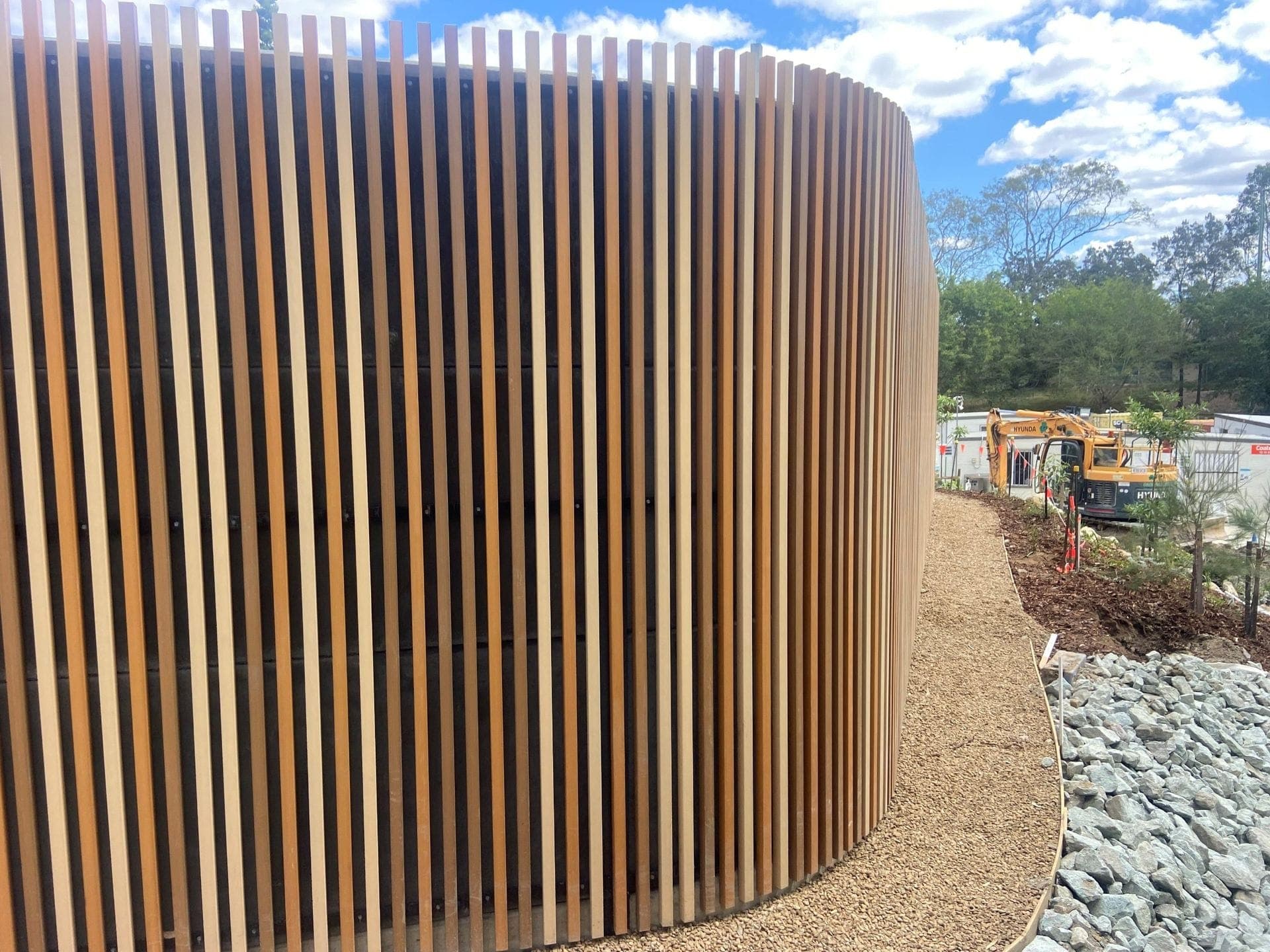 Curved timber slat acoustic barrier with landscaping