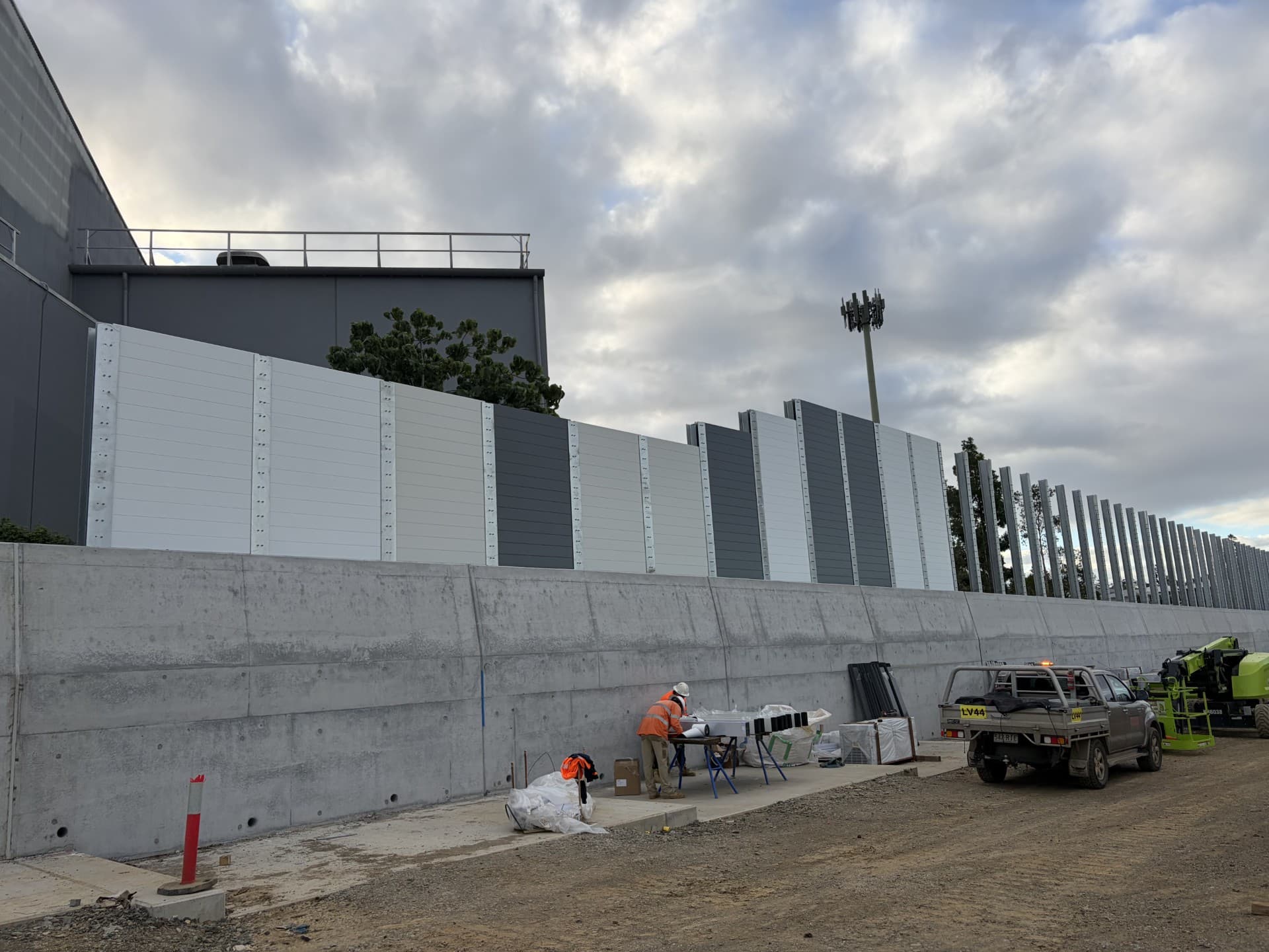White and charcoal aluminium noise wall panels above a concrete plinth