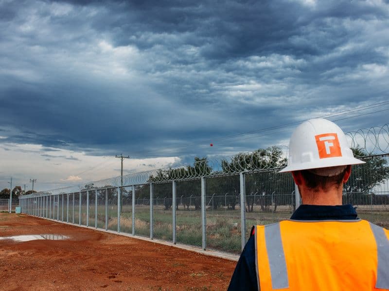 Fencepac crew member in branded hard hat and hi-vis on a fencing site