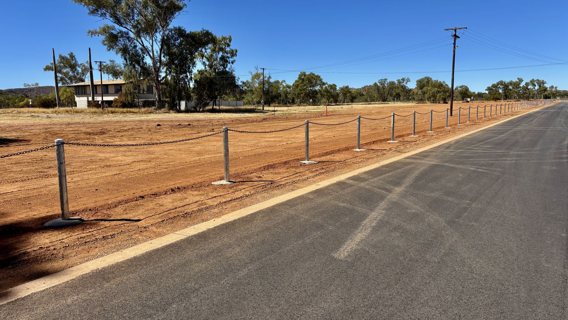 Galvanised bollard and chain posts on red earth