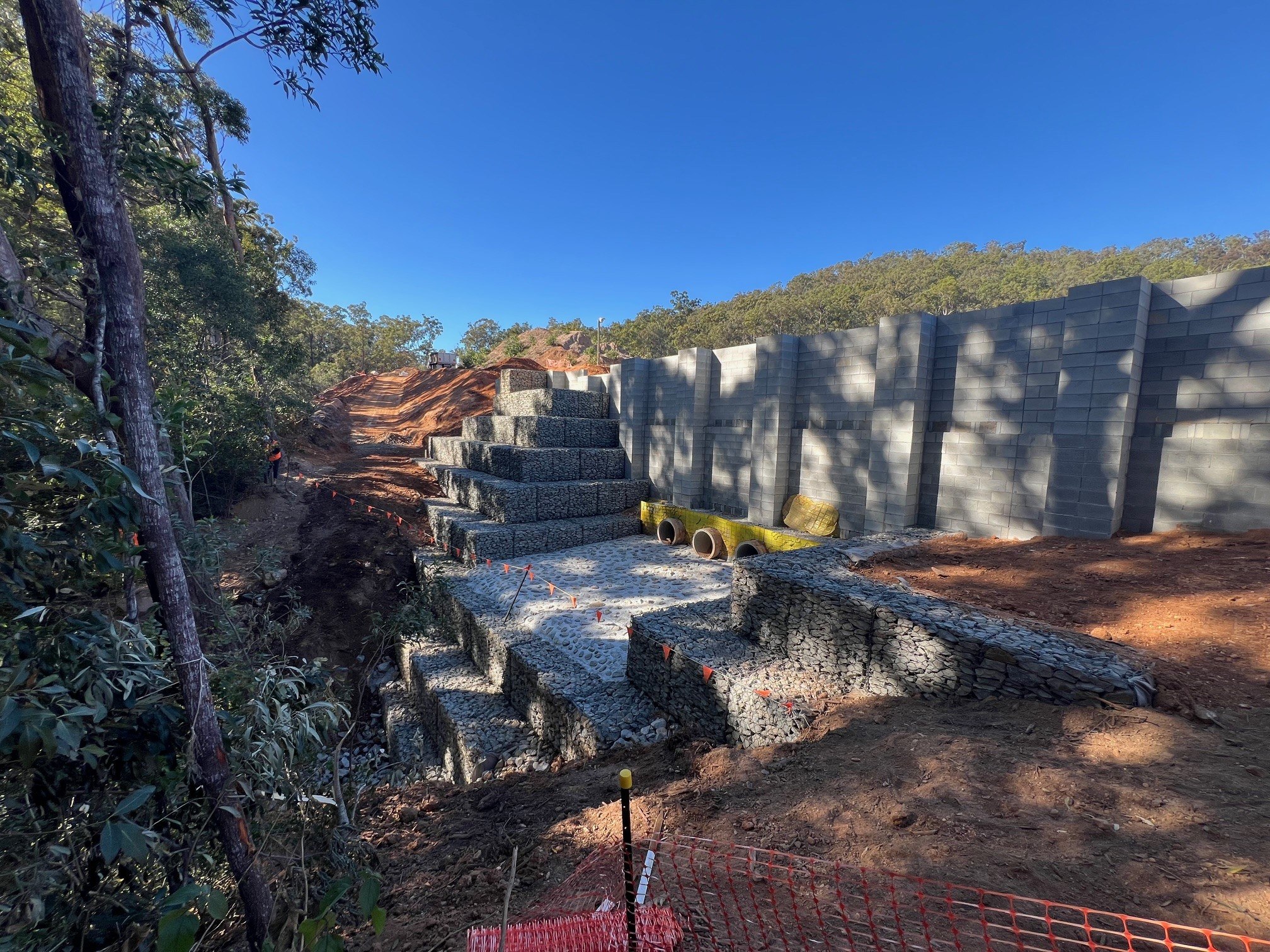 Massive gabion retaining wall aerial view with red earth and bushland