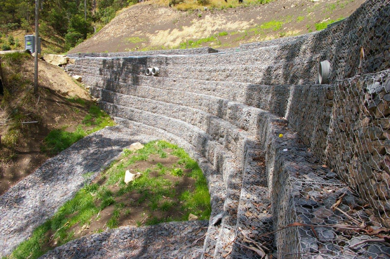 Massive gabion retaining wall aerial view with red earth and bushland