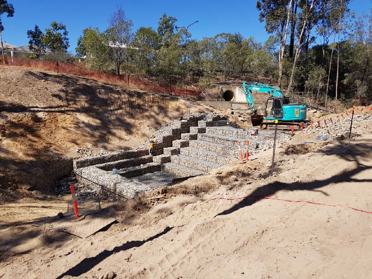 Massive gabion retaining wall aerial view with red earth and bushland