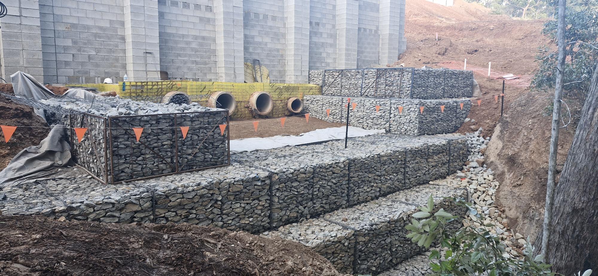 Massive gabion retaining wall aerial view with red earth and bushland