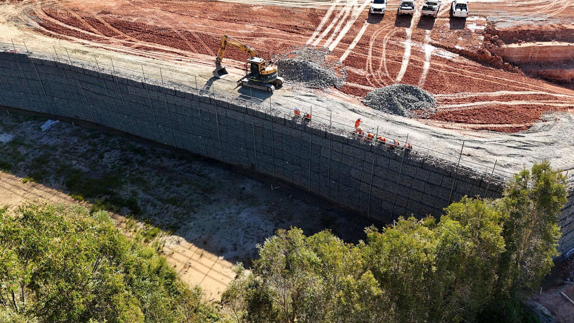 Massive gabion retaining wall aerial view with red earth and bushland