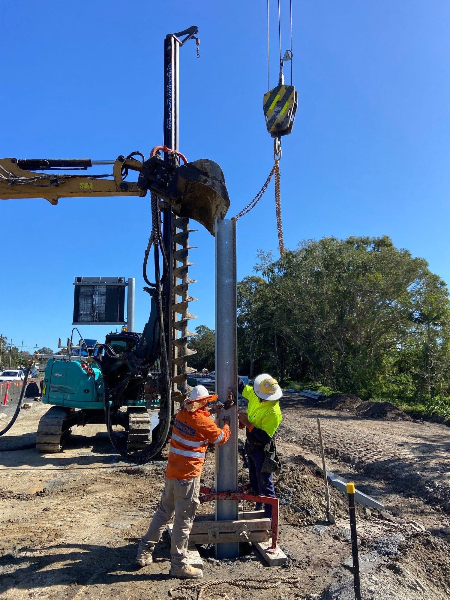 Crew installing steel posts with auger and crane